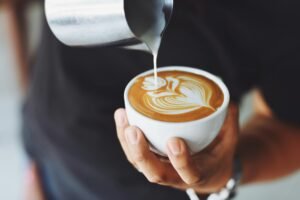 pexels-photo-302899-302899 Close-up of a barista pouring milk to create latte art in a coffee cup.
